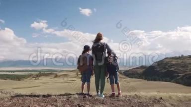全家游客。 一个年轻的女人，带着孩子走在山上的一条小路上。 年轻的母亲和孩子